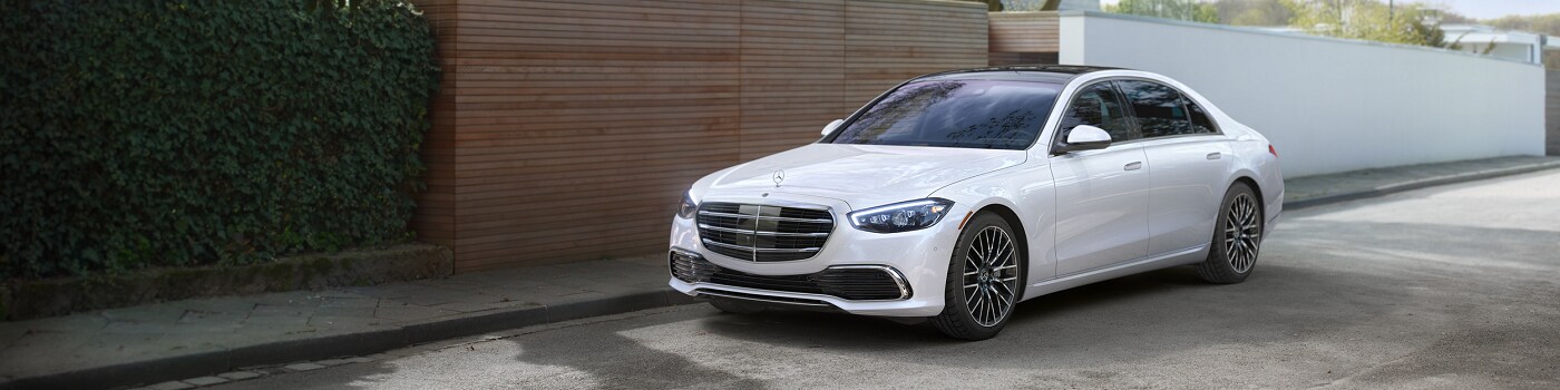 White Mercedes-Benz S-Class parked by a modern house